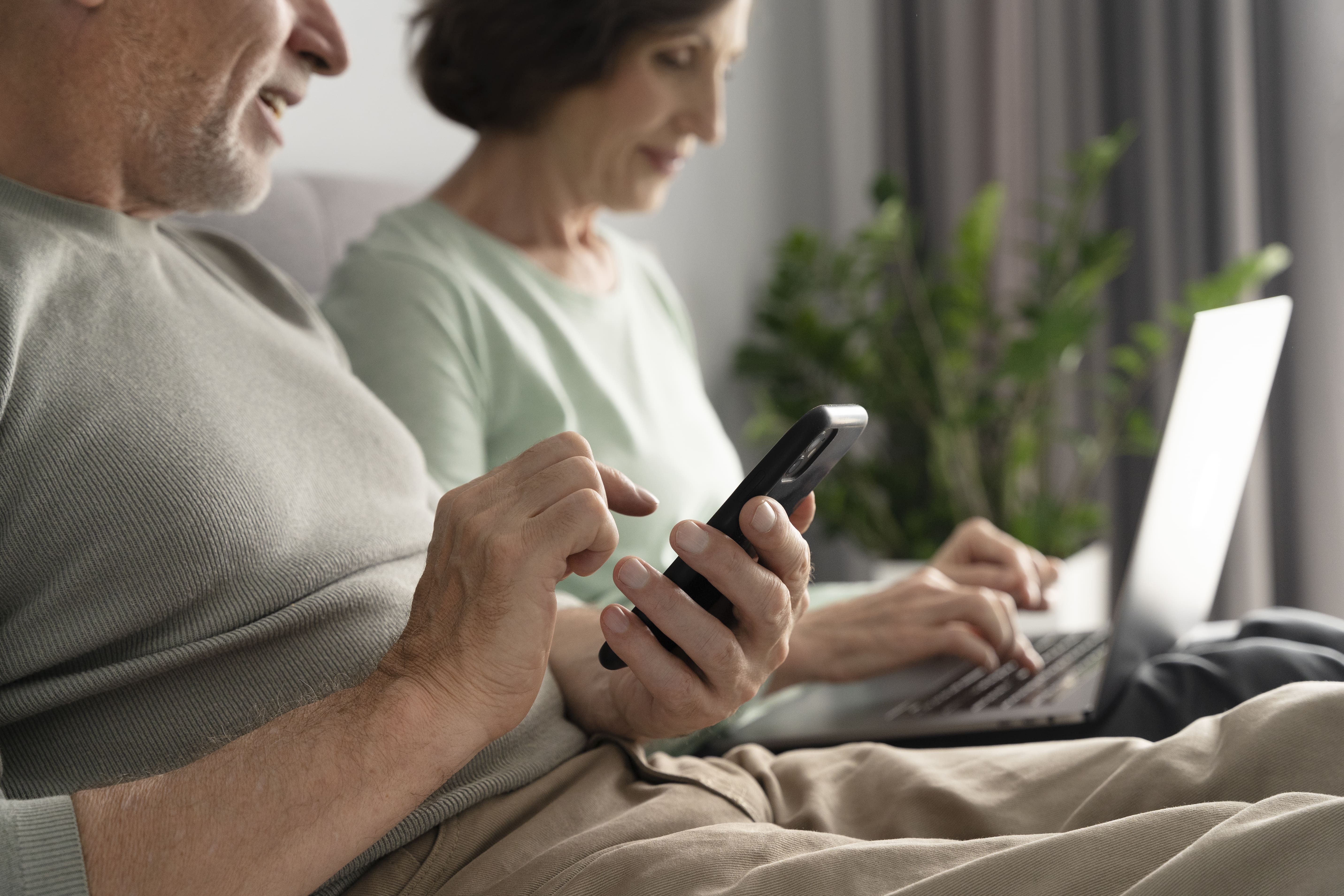 close up senior couple using phone and laptop