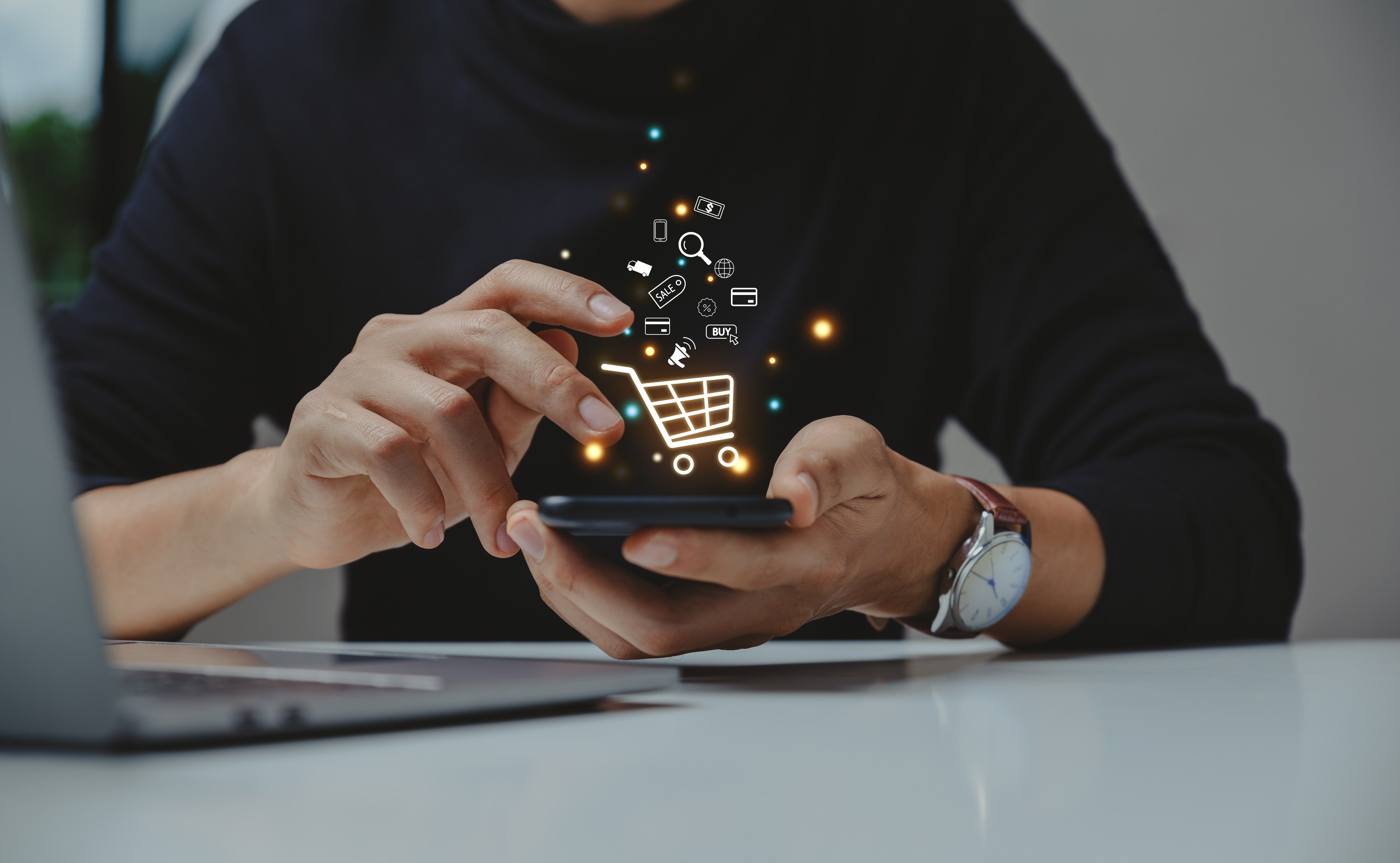 Young man using smartphone with shopping cart icon